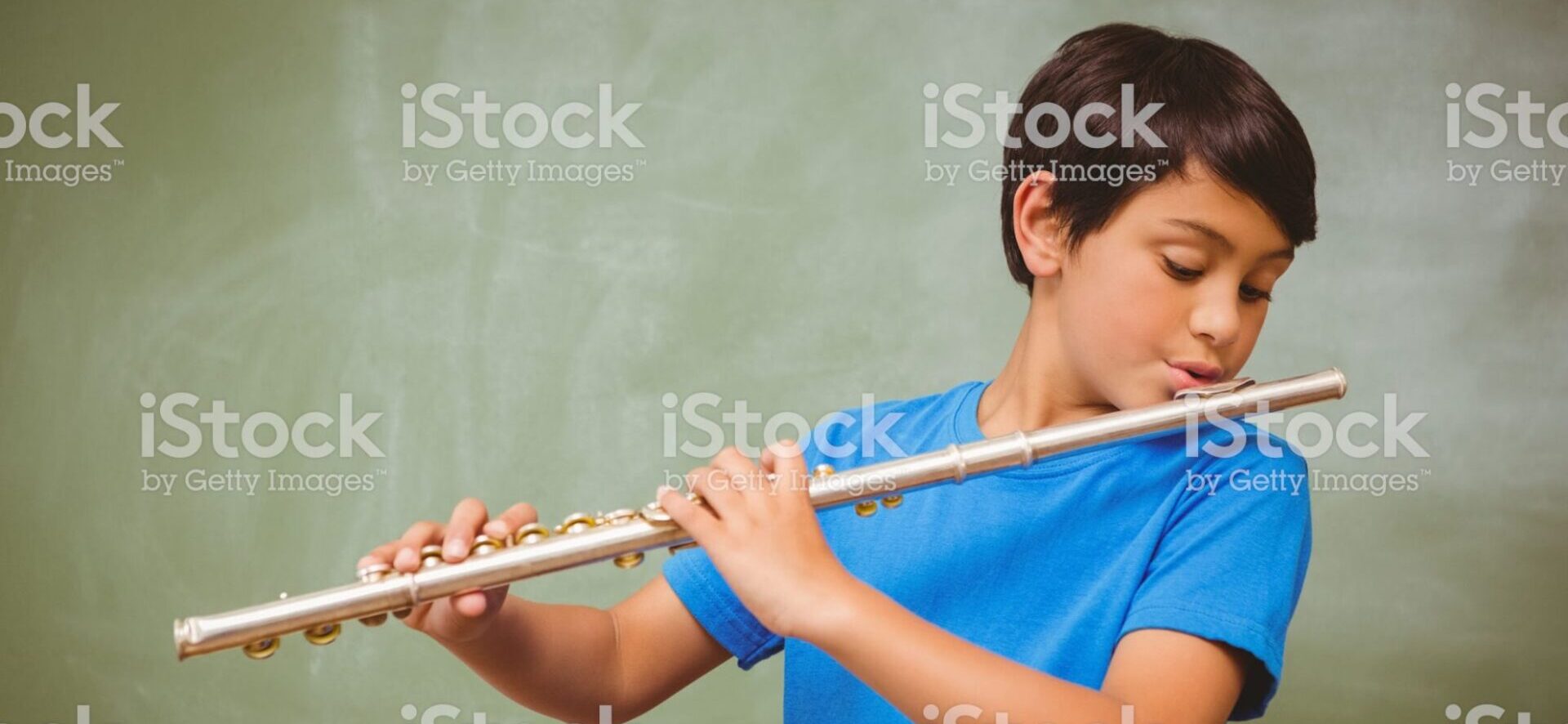 Portrait of cute little boy playing flute in classroom